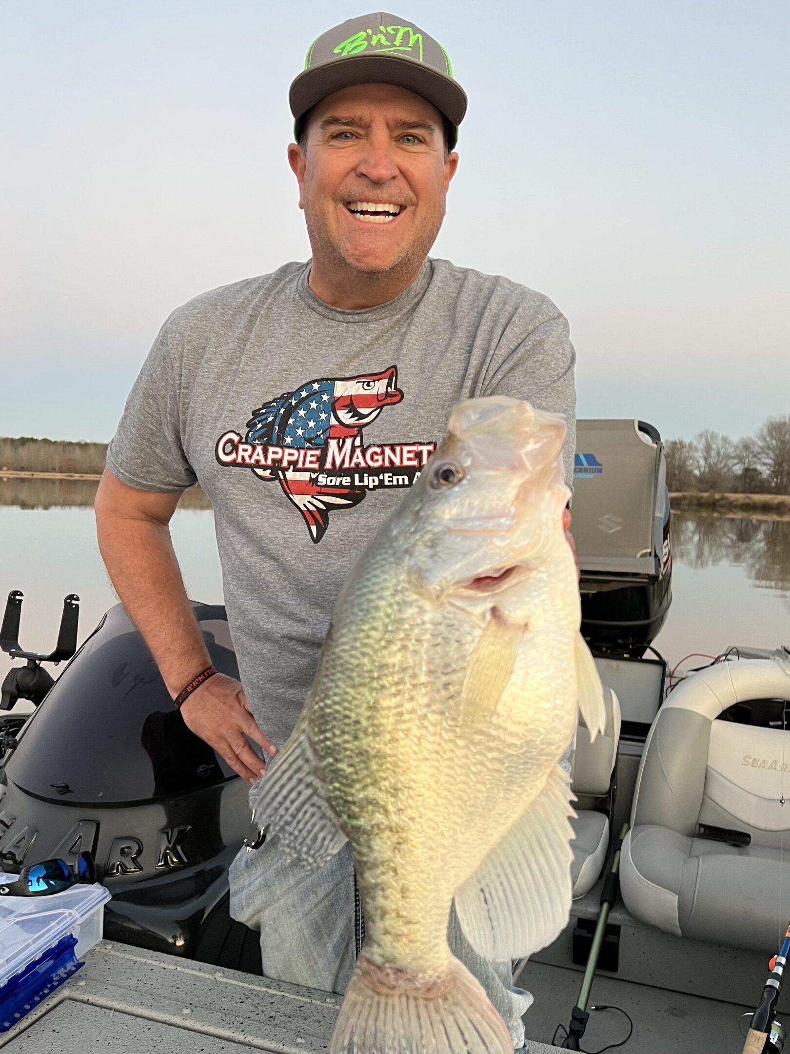Man proudly holds a large fish on a boat.